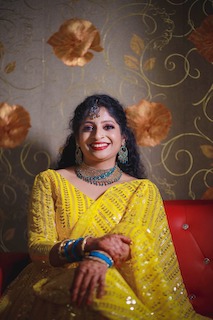 Bride dressed in yellow saree and blue ornaments for her reception. Makeup dont by Persona